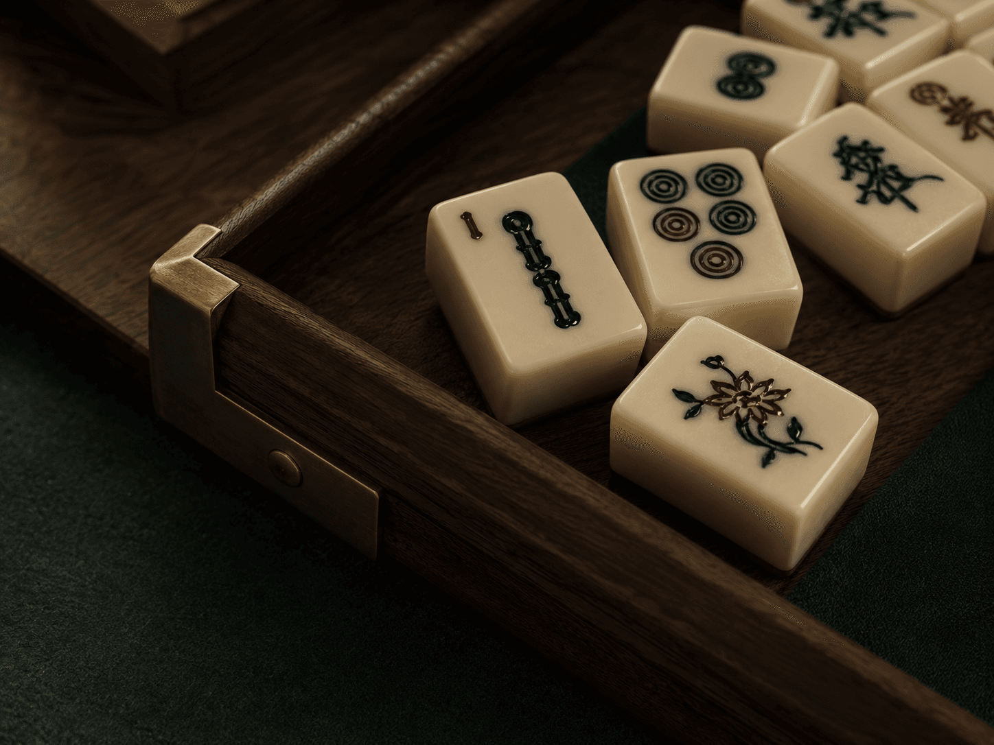 Close-up of ivory mahjong tiles with hand-filled engraving, resting in a walnut case with brass corner hardware