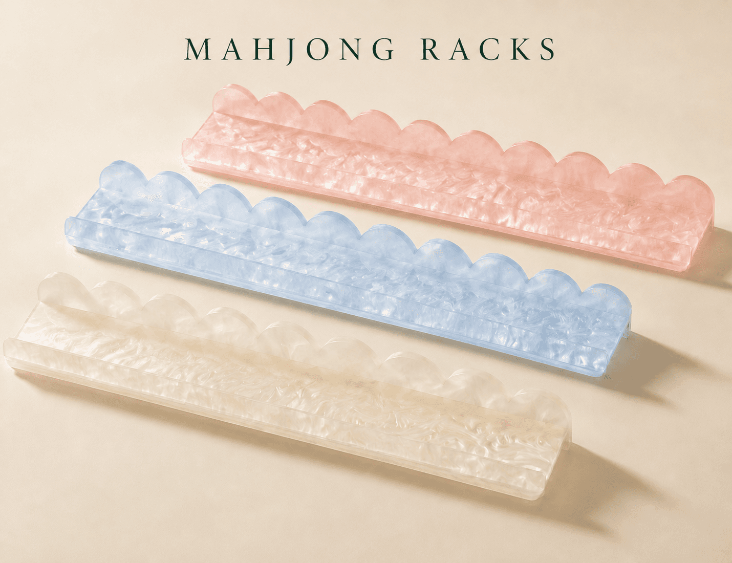 Three scalloped marbled mahjong racks in blush, blue, and pearl finishes